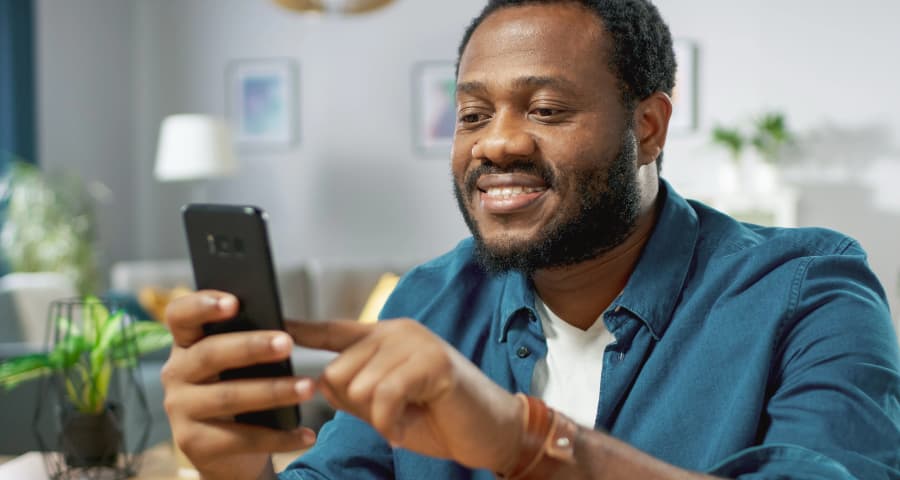 Man in his home interacting with an app on his phone